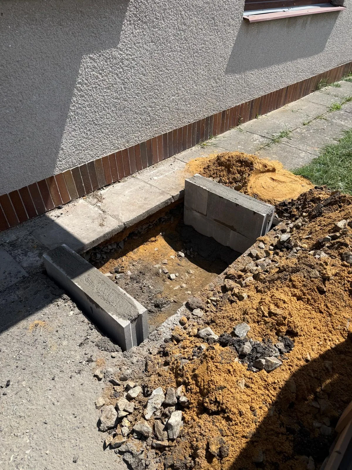Základové podpory pro venkovní technologii v připravené ploše u domu.