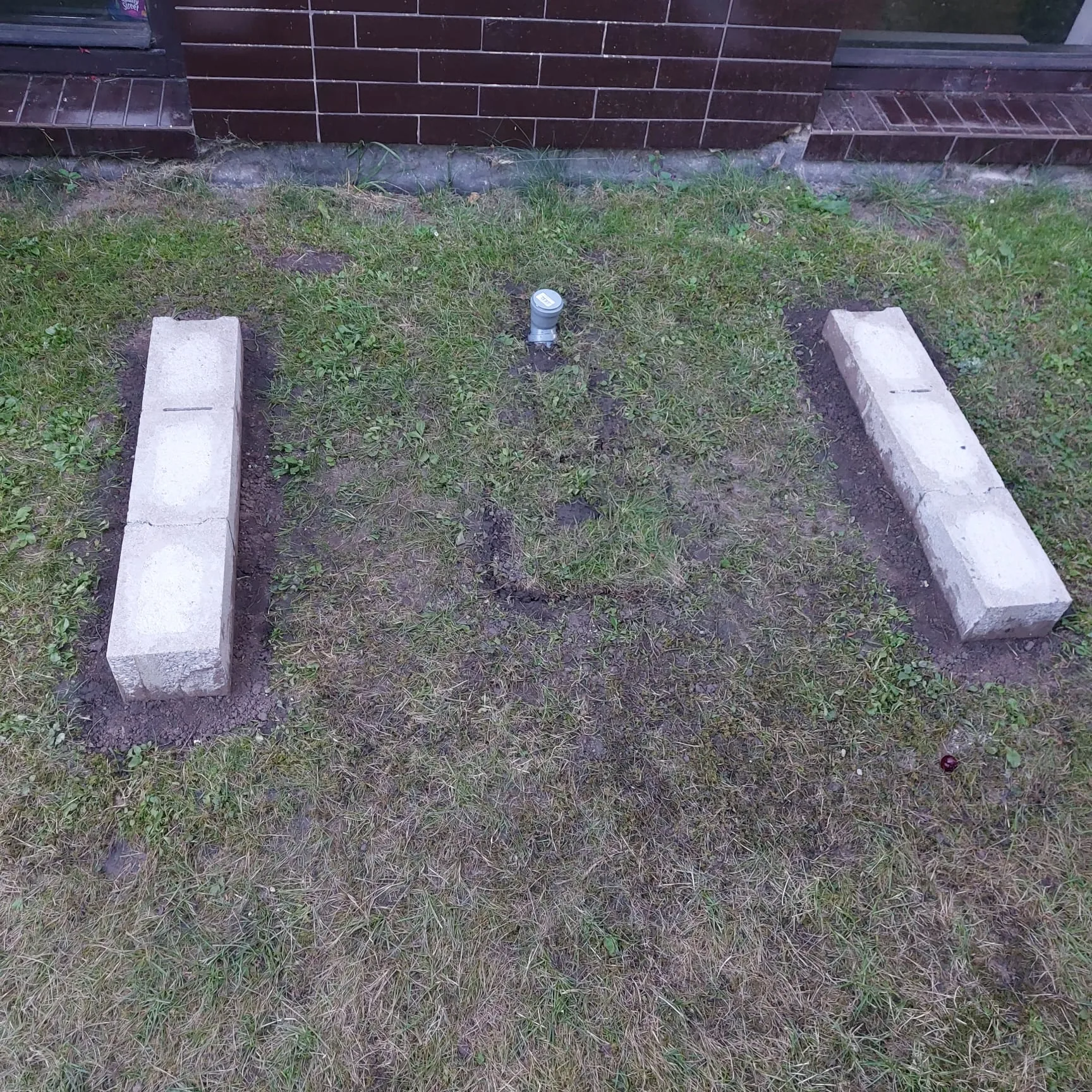 Dvě betonové podpory v terénu před umístěním venkovní technologie.