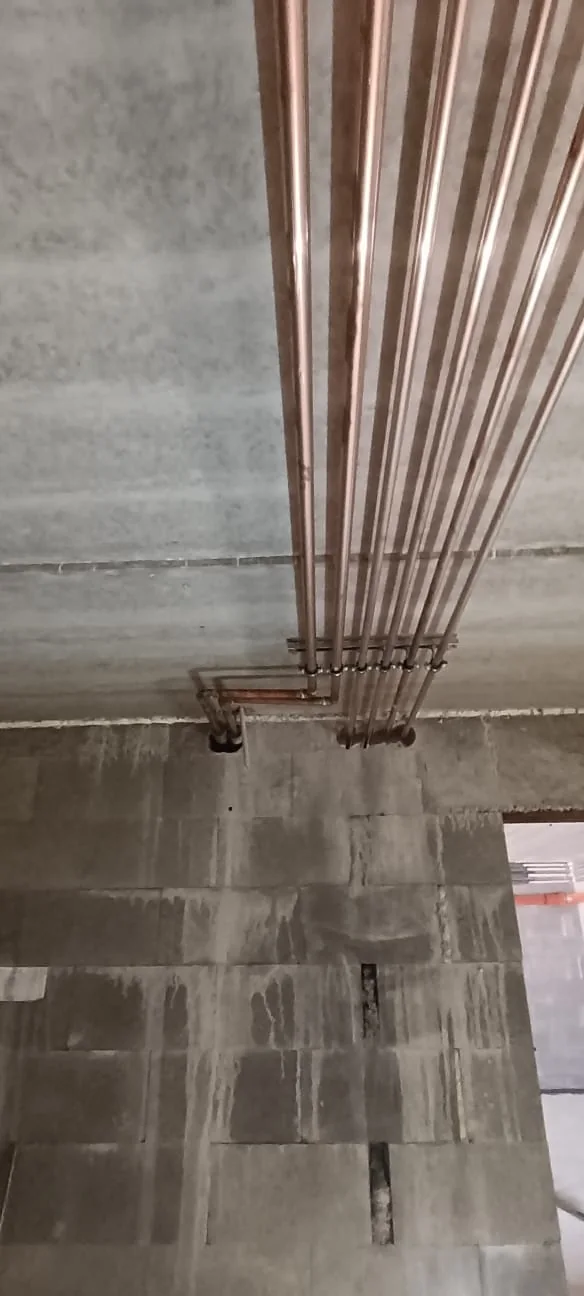 Dům s dílnou a dvěma byty. Montáž měděných rozvodů pod stropem.